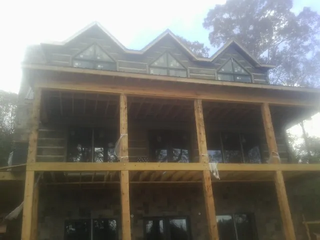 Dormers and porch framing on a large log home under construction — Roof Coating work by our crew in Crabtree