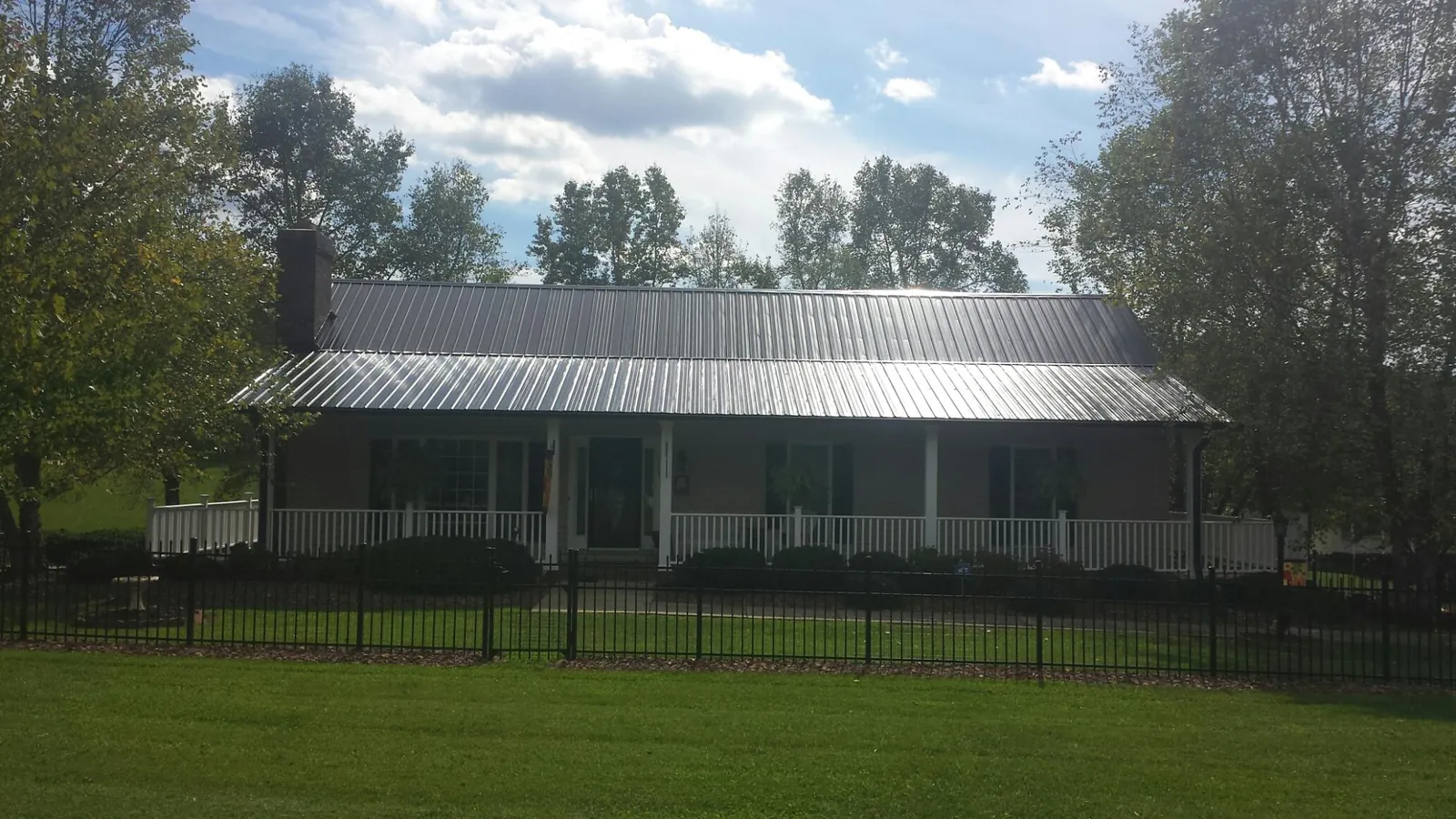 Gray metal roof on a brick ranch with a full width front porch — Gutter Guard Installation work by our crew in Crabtree